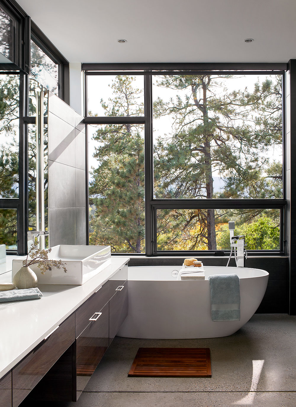 Modern bathroom with large awning windows and forest view
