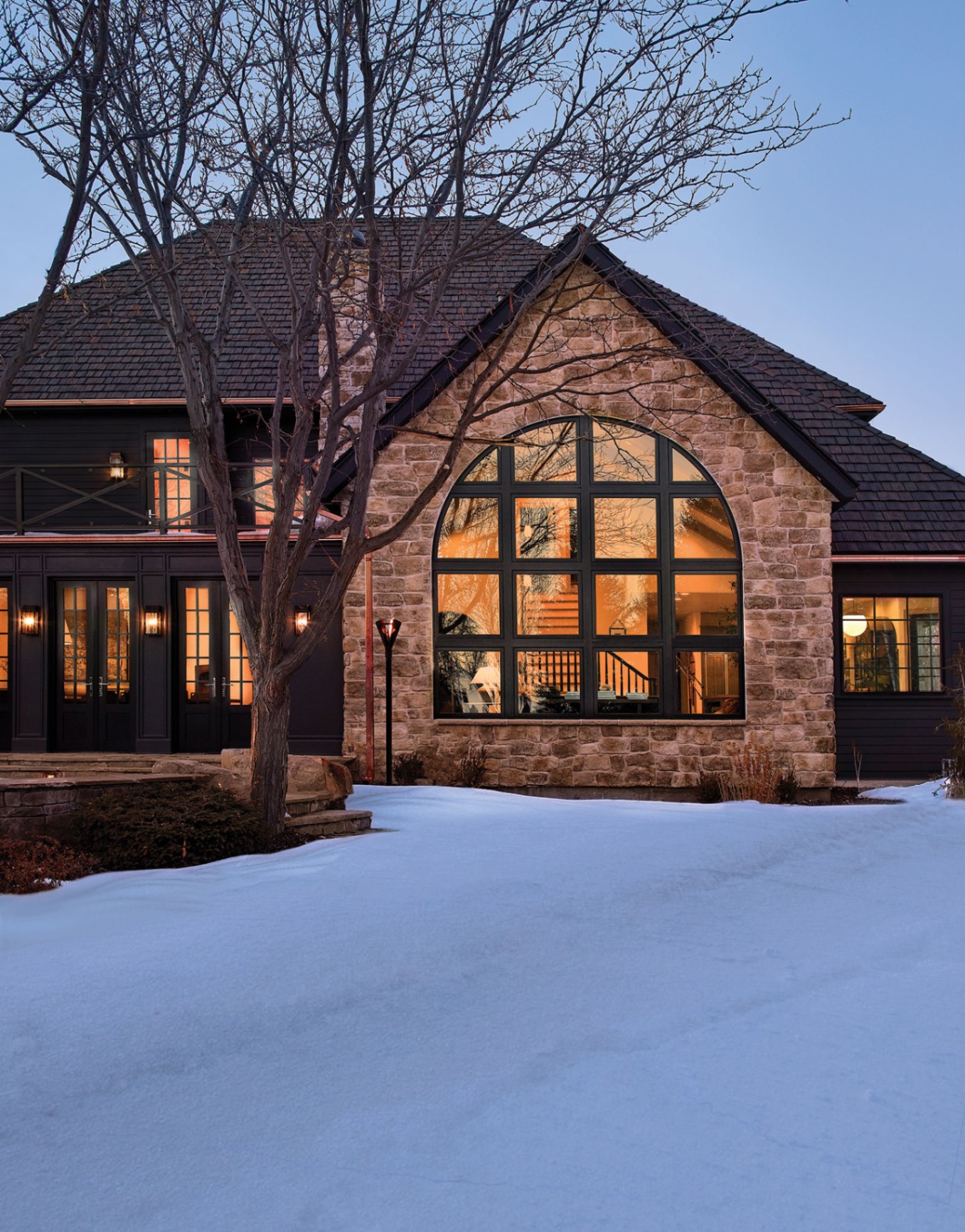 Arched picture window on stone home at dusk